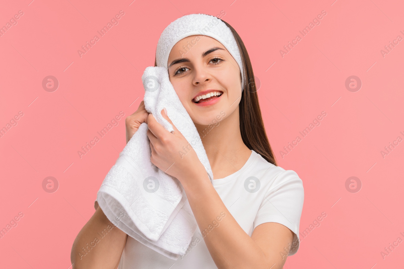 Photo of Washing face. Young woman with headband and towel on pink background