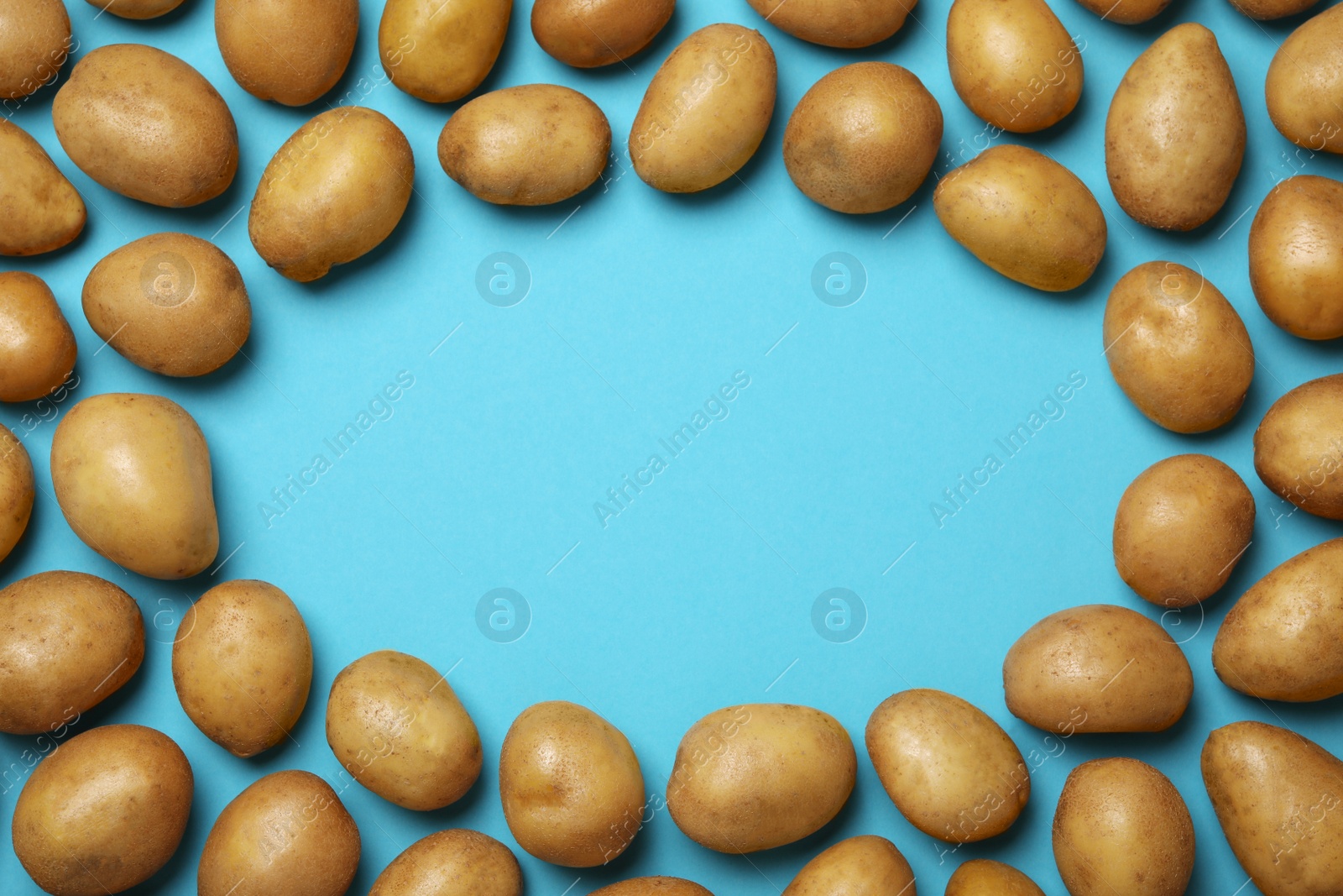 Photo of Frame made of raw fresh organic potatoes on blue background, flat lay. Space for text