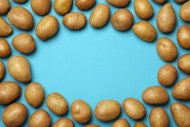 Photo of Frame made of raw fresh organic potatoes on blue background, flat lay. Space for text