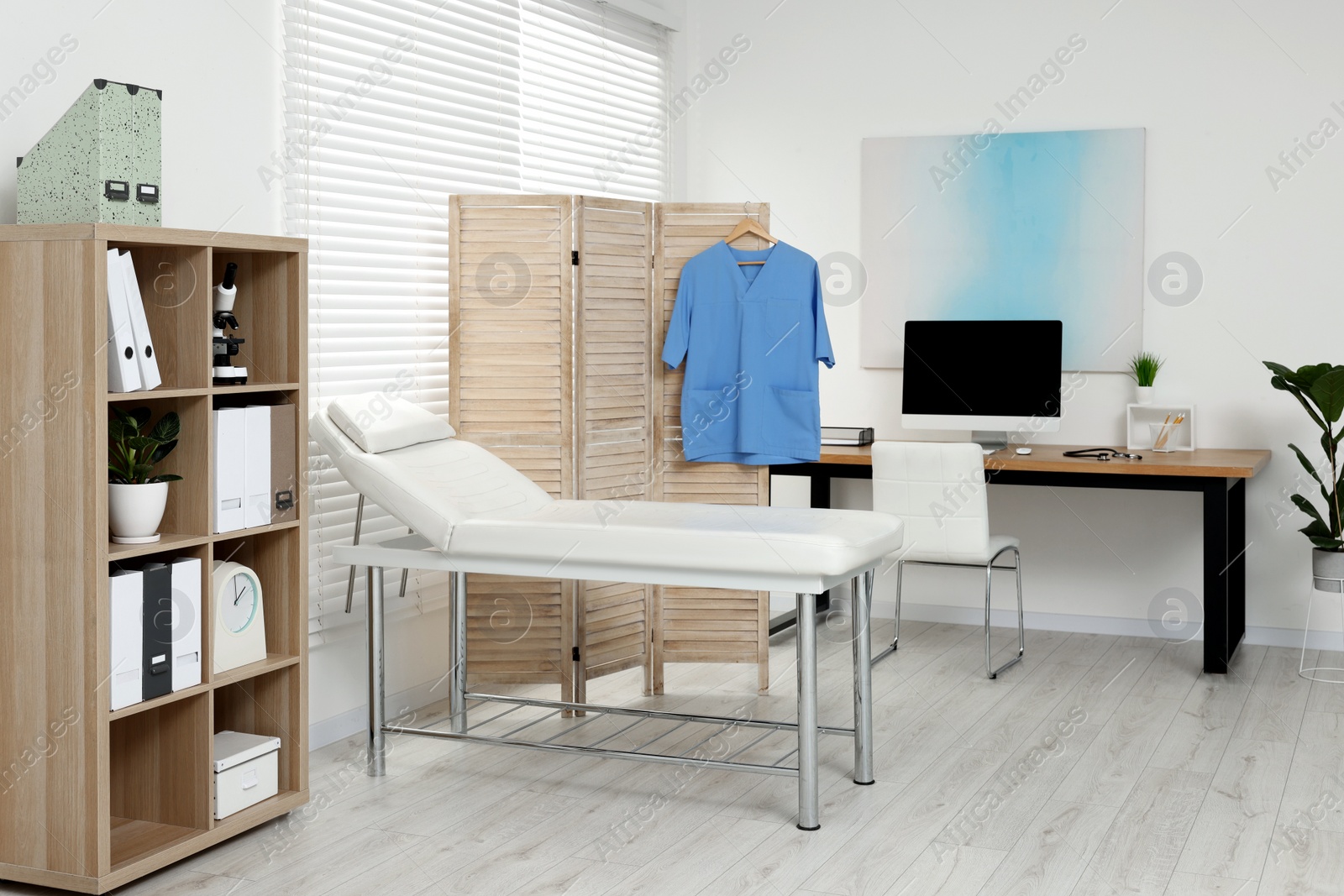 Photo of Modern medical office with doctor's workplace and examination table in clinic