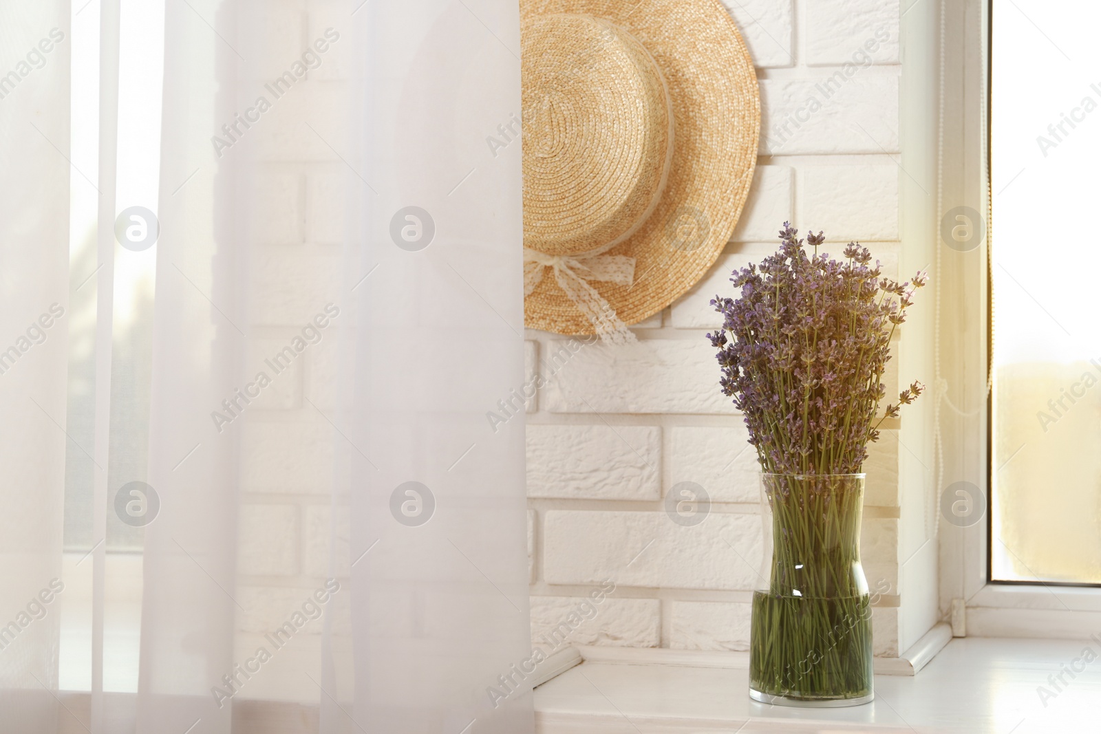 Photo of Beautiful lavender bouquet and straw hat near window indoors