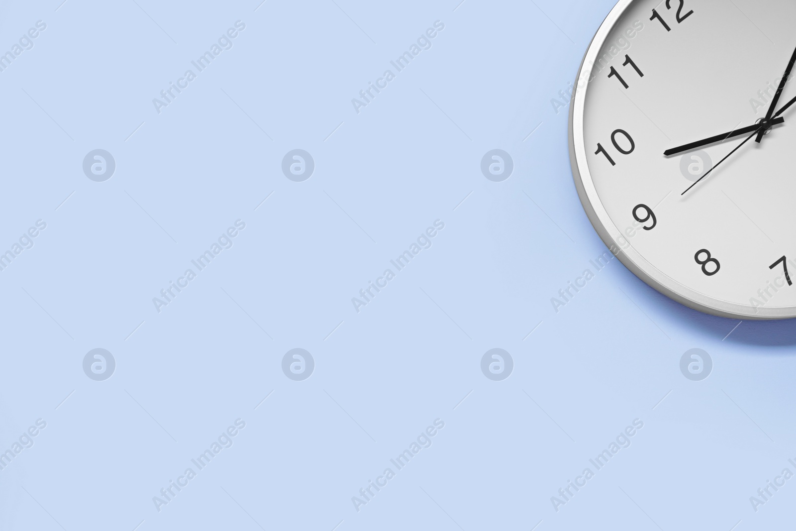 Photo of Stylish round clock on light blue background, top view with space for text. Interior element