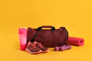 Sports bag and gym equipment on yellow background