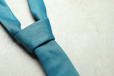 Photo of One blue necktie on light textured table, above view. Space for text