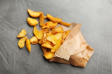 Photo of Delicious oven baked potatoes with parchment on grey background, top view