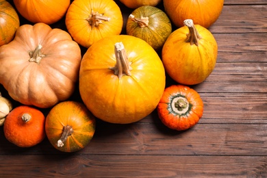 Photo of Many fresh raw whole pumpkins on wooden background, flat lay. Holiday decoration