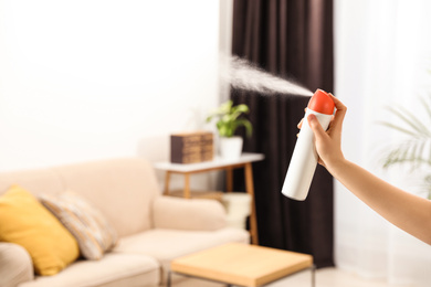 Woman spraying air freshener at home, closeup