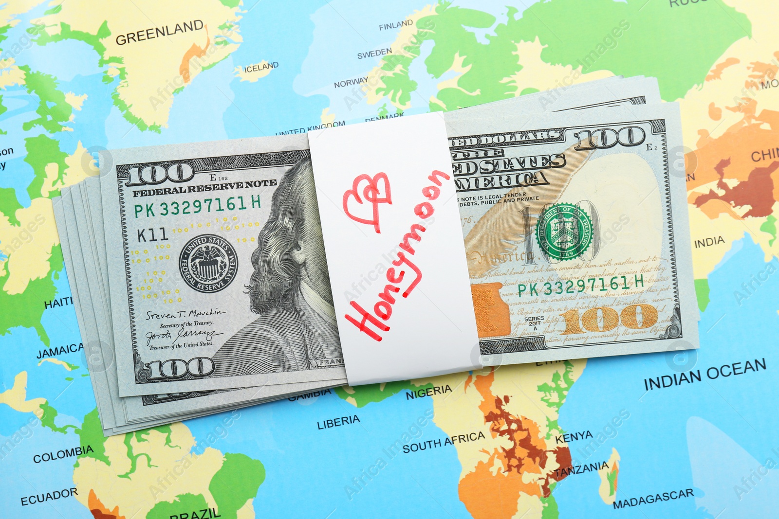 Photo of Stack of money with word Honeymoon on world map, top view