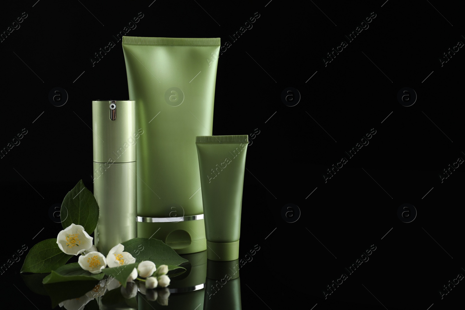 Photo of Set of cosmetic products and flowers on black background, space for text