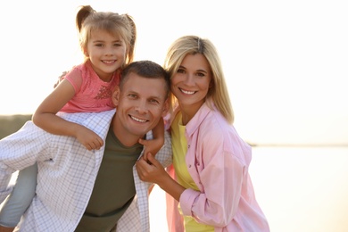 Photo of Happy parents with their child on beach. Spending time in nature