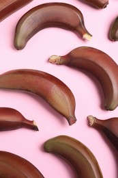 Tasty red baby bananas on pink background, flat lay