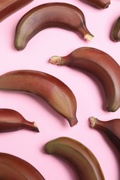 Photo of Tasty red baby bananas on pink background, flat lay