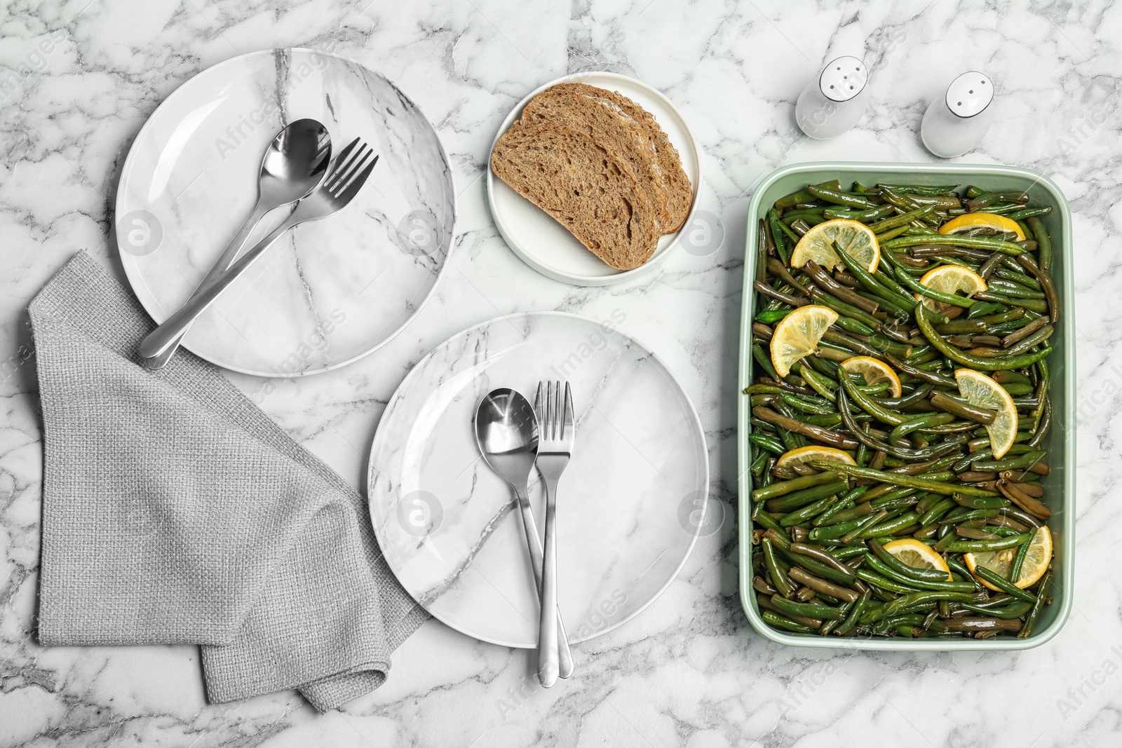 Photo of Dish with tasty green beans and lemons served for dinner on marble table, top view