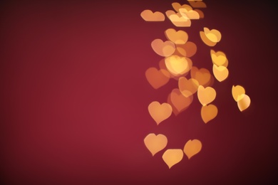 Photo of Blurred view of beautiful lights on burgundy background, space for text. Bokeh effect