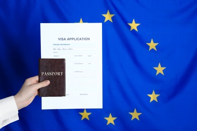 Photo of Woman holding visa application form and passport against European Union flag, closeup. Space for text