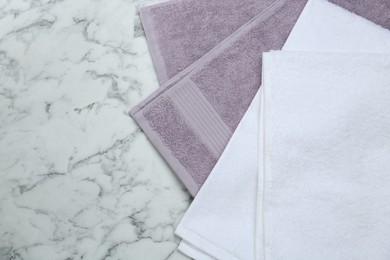 Photo of Different terry towels on white marble table, flat lay. Space for text