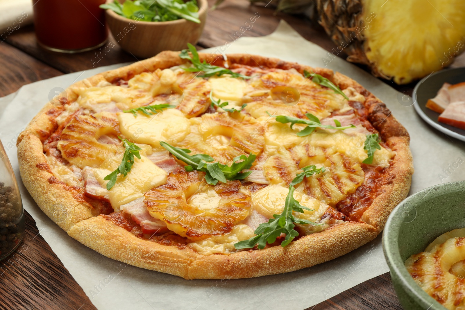 Photo of Delicious pineapple pizza with arugula on wooden table, closeup