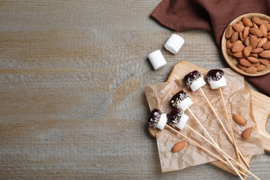 Photo of Delicious marshmallows covered with chocolate on wooden table, flat lay. Space for text