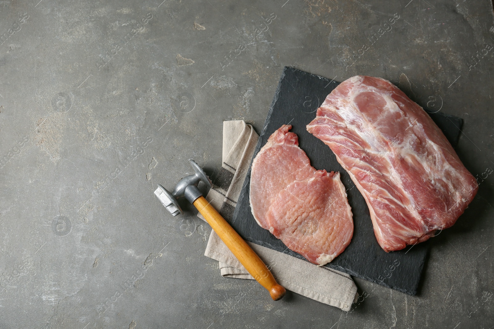 Photo of Cooking schnitzel. Raw pork chops with meat mallet on grey table, flat lay and space for text