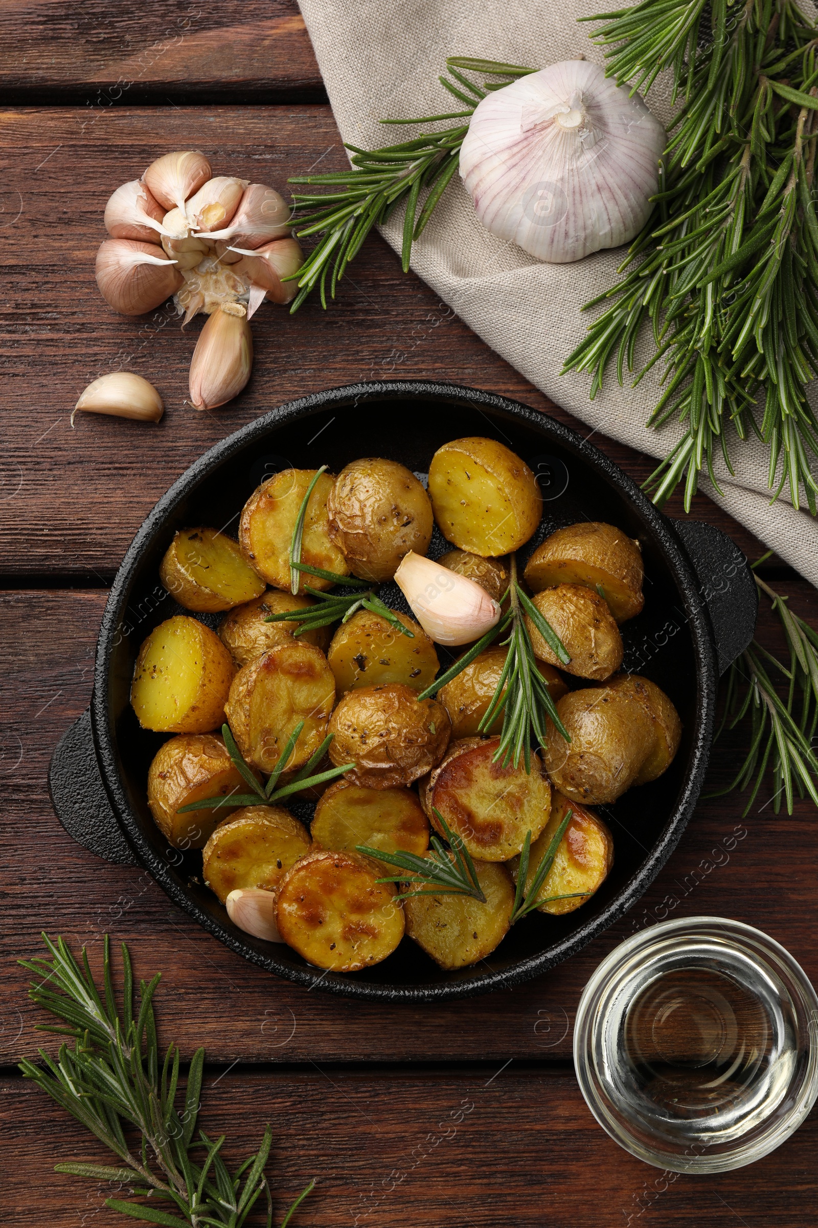 Photo of Delicious baked potatoes with rosemary and ingredients on wooden table, flat lay