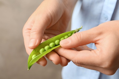 Photo of Young woman shelling fresh green peas, closeup