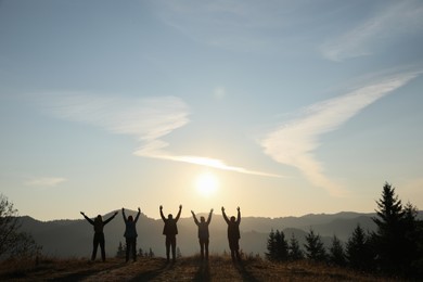 Photo of Group of people enjoying sunrise in mountains, back view. Space for text
