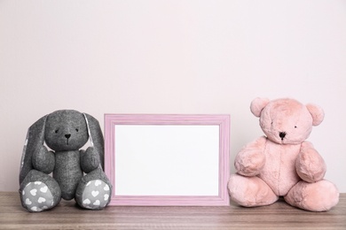 Photo of Photo frame and adorable toys on table against light background, space for text. Child room elements