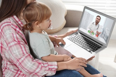 Image of Mother and daughter having online consultation with pediatrician via laptop on sofa at home