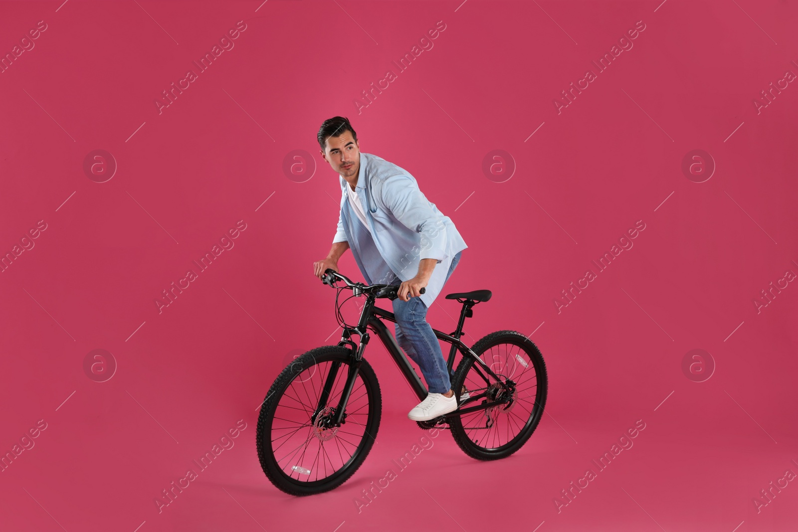 Photo of Handsome young man with modern bicycle on pink background