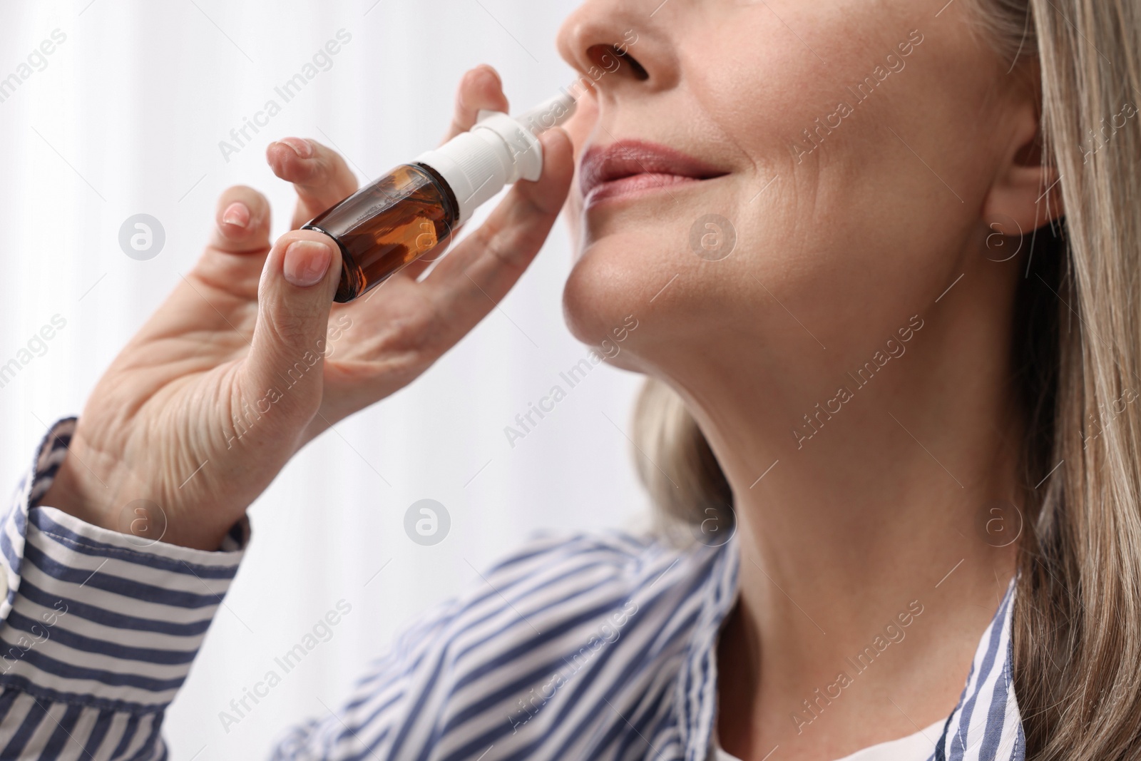 Photo of Medical drops. Woman using nasal spray indoors, closeup