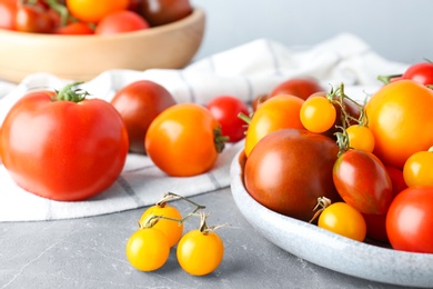 Many fresh ripe yellow and red tomatoes on grey marble table