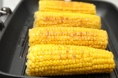 Photo of Fresh corn cobs on grill pan, closeup