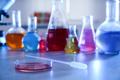 Petri dish with pipette on table against blurred background, space for text. Chemistry glassware