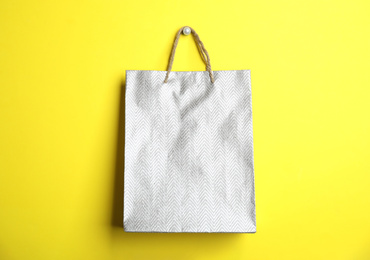 Photo of Silver shopping paper bag on yellow background