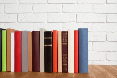 Books on wooden table near white brick wall