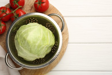 Photo of Wet cabbage in colander and tomatoes on white wooden table, top view. Space for text