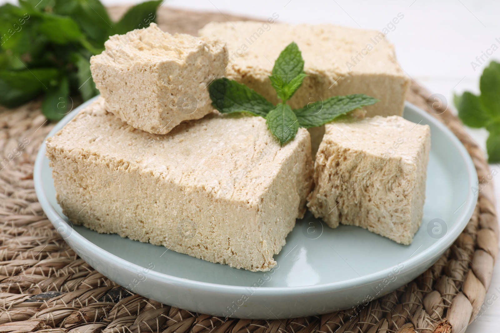 Photo of Pieces of tasty halva and mint on table, closeup