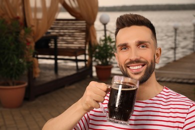 Photo of Man with glass of dark beer in outdoor cafe, space for text