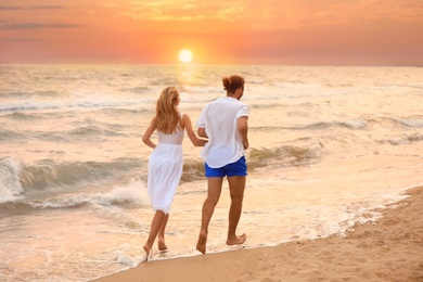 Photo of Young couple having fun on beach at sunset