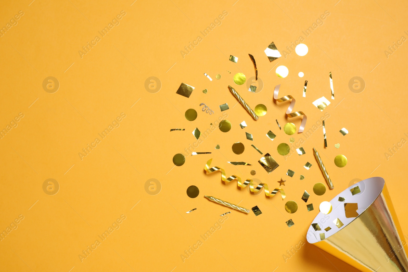 Photo of Party cone with shiny confetti on orange background, flat lay. Space for text