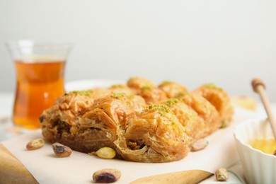 Photo of Delicious sweet baklava with pistachios on wooden board, closeup