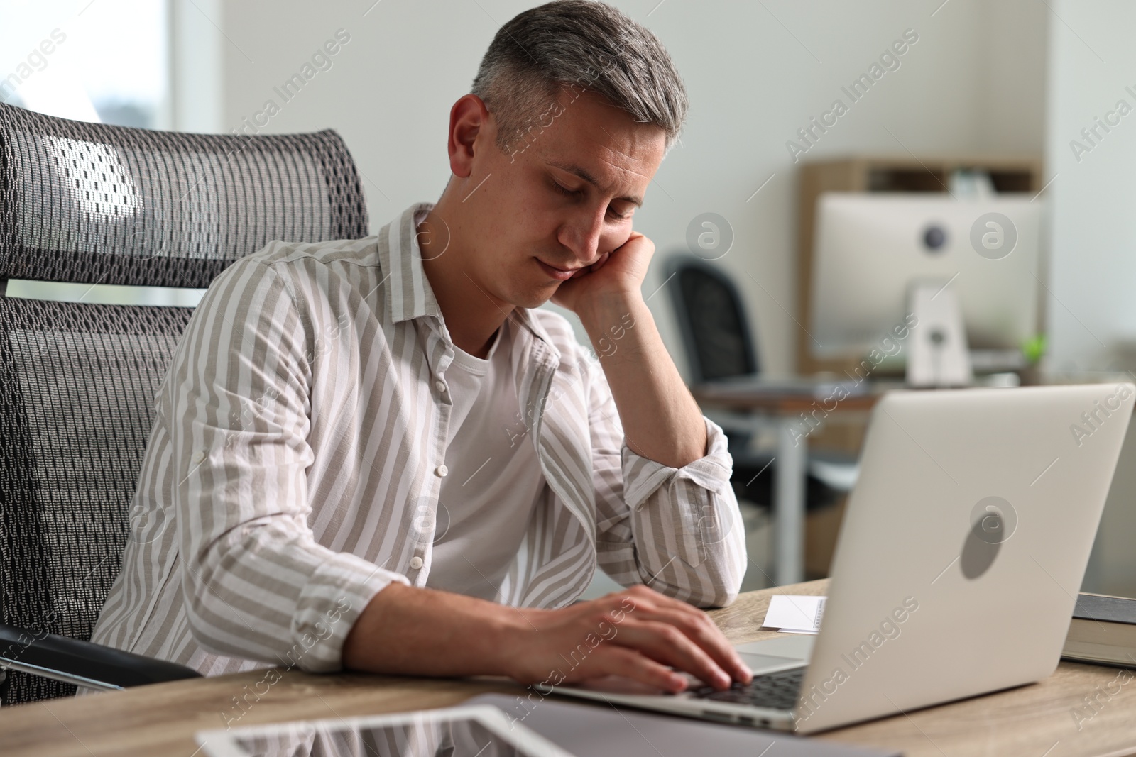 Photo of Man snoozing at wooden table in office