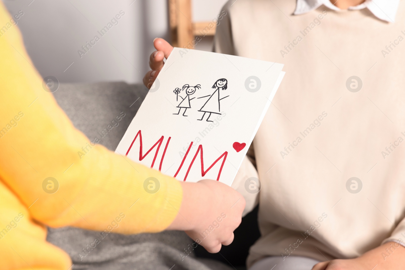Photo of Woman receiving greeting card from her daughter at home, closeup