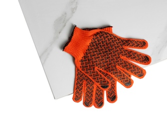 Ceramic tiles and gloves on white background, top view
