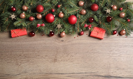 Fir tree branches with Christmas decoration on wooden background, flat lay. Space for text