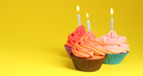 Delicious birthday cupcakes with bright cream on yellow background. Banner design and space for text