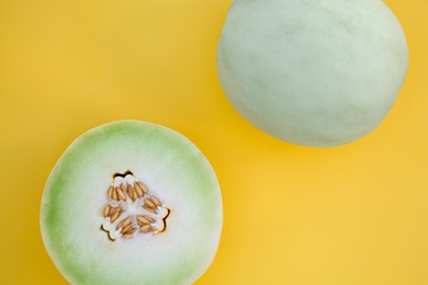 Photo of Whole and cut fresh ripe honeydew melons on yellow background, flat lay