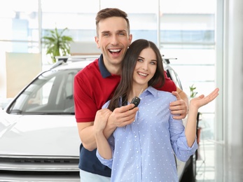 Photo of Young couple with key in salon. Buying new car
