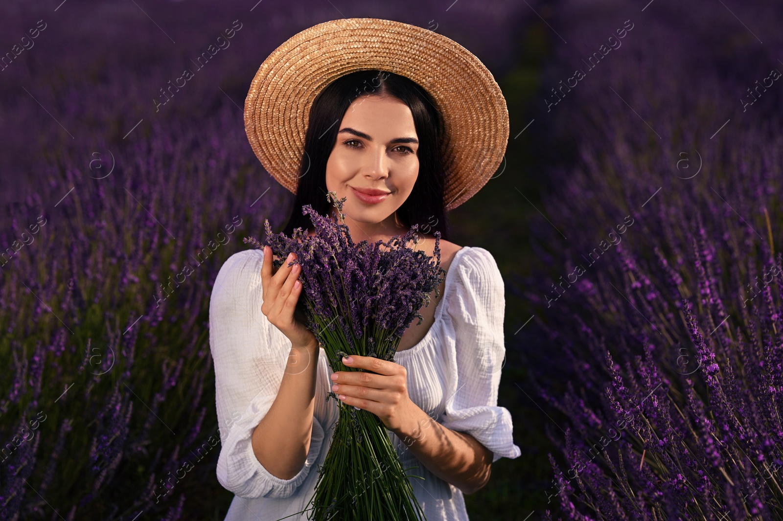 Photo of Beautiful young woman with bouquet in lavender field