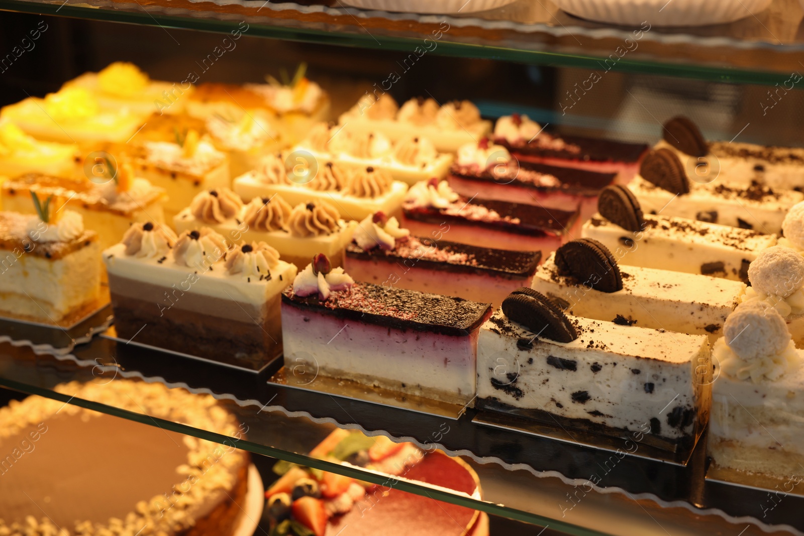 Photo of Different delicious cakes on counter in bakery shop, closeup